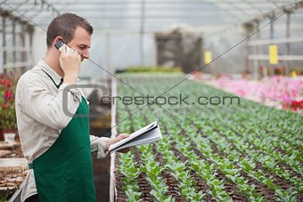 Gardener calling and taking notes in greenhouse