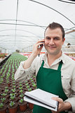 Worker taking notes and calling in greenhouse