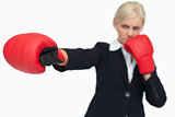 Blonde businesswoman with red gloves boxing