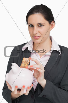 Brunette putting money into a piggy-bank