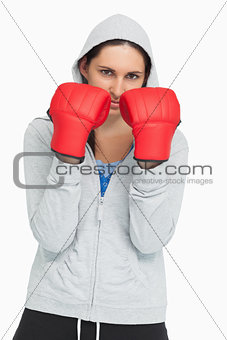 Serious brunette in sweatshirt wearing boxing gloves