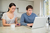 Woman holding credit card with man on laptop