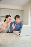 Smiling couple using video chat on laptop