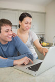 Smiling young couple using laptop