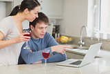 Couple drinking red wine and using laptop