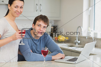 Young couple using laptop drinking red wine