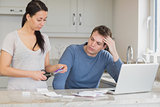 Wife cutting up credit card with husband watching