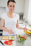 Young woman tossing salad for sandwich