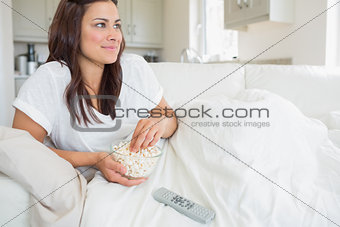 Woman watching television and eating popcorn