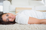 Brunette relaxing on the carpet with moving boxes