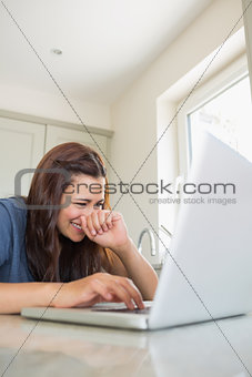 Woman typing on laptop while laughing