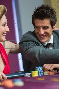 Couple smiling at each other at roulette table