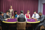 People sitting at the casino table with woman standing