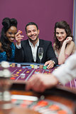 Man and women sitting at roulette table smiling