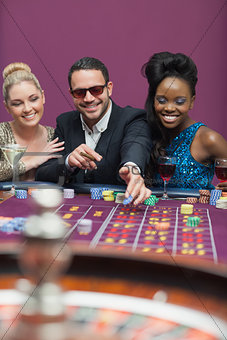 Man wearing sun glasses with women at roulette