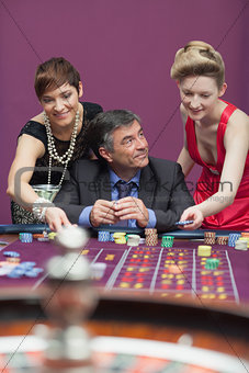 Woman placing bet for man at roulette