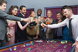 People standing clinking glasses at roulette table