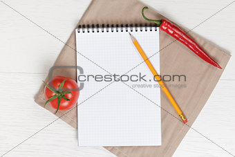 recipe notepad on wooden table with pepper and tomato