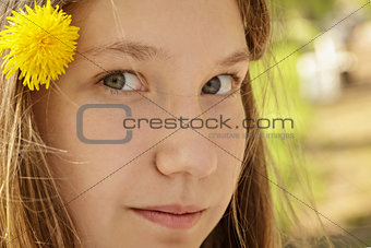 portrait of young teenager girl in park with dandelion in hair