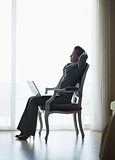 Silhouette of relaxed business woman sitting in hotel room with 