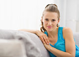 Portrait of happy young woman sitting on sofa in living room