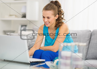 Happy young woman with laptop in living room