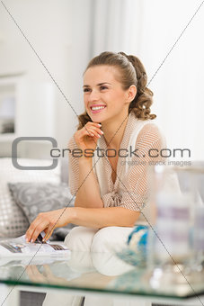 Portrait of thoughtful young housewife sitting on sofa in living