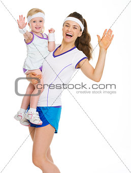 Smiling mother and baby in tennis clothes greeting