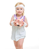 Baby in tennis clothes holding piggy bank