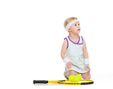 Baby in tennis clothes with racket and balls looking on copy spa