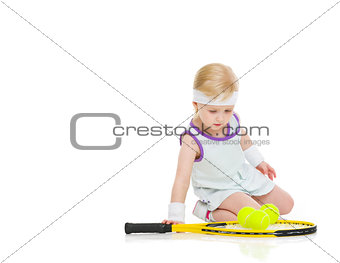 Baby in tennis clothes with racket and balls