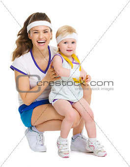 Portrait of mother and baby in tennis clothes with medal