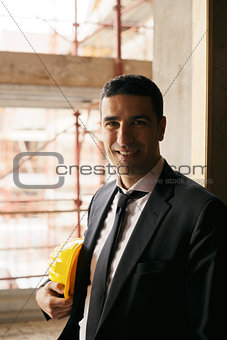 Engineer with helmet in construction site smiling at camera, por