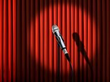Microphone under spotlight over red curtains