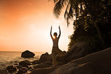  girl silhouette performing yoga on beach during a beautiful sun