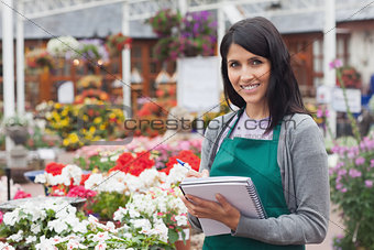 Employee making notes on the flowers in garden center