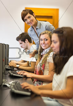 Students sitting at the computer teacher smiling