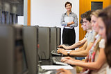 Teacher standing while students sitting at the computer