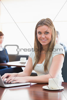 Student sitting at the coffee shop smiling with her laptop