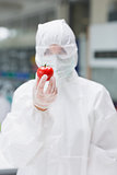 Woman wearing protective suit holding a tomato