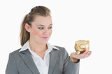 Woman smiling at the piggy bank in her hand