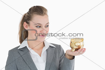 Woman smiling at the piggy bank in her hand