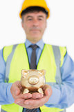 Smiling architect holding piggy bank