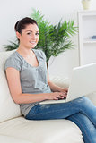 Smiling woman on the couch with a laptop