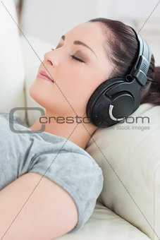 Young woman lying on the couch and listening to music