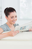 Smiling woman reading the news while sitting on a couch