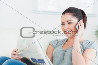Phoning woman reading the newspaper on the couch