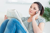 Phoning woman sitting on the couch and reading the news