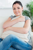 Woman sitting on the couch hugging a pillow