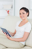 Smiling woman on the couch using a tablet pc